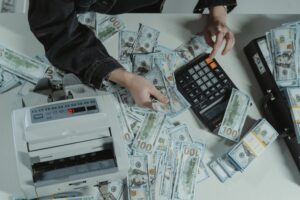 person holding dollar bills while using a calculator